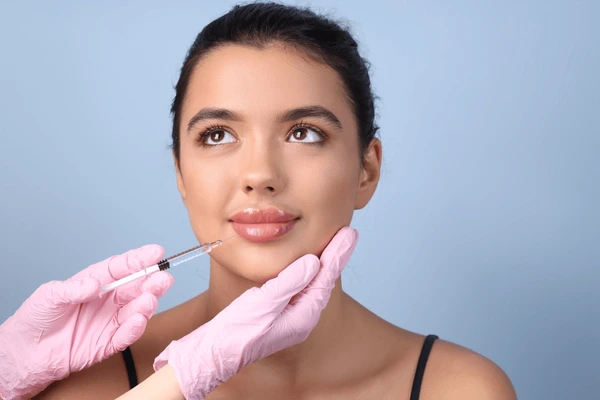 Young woman receiving Juvederm Volbella XC lip filler injection, enhancing lips and reducing fine lines